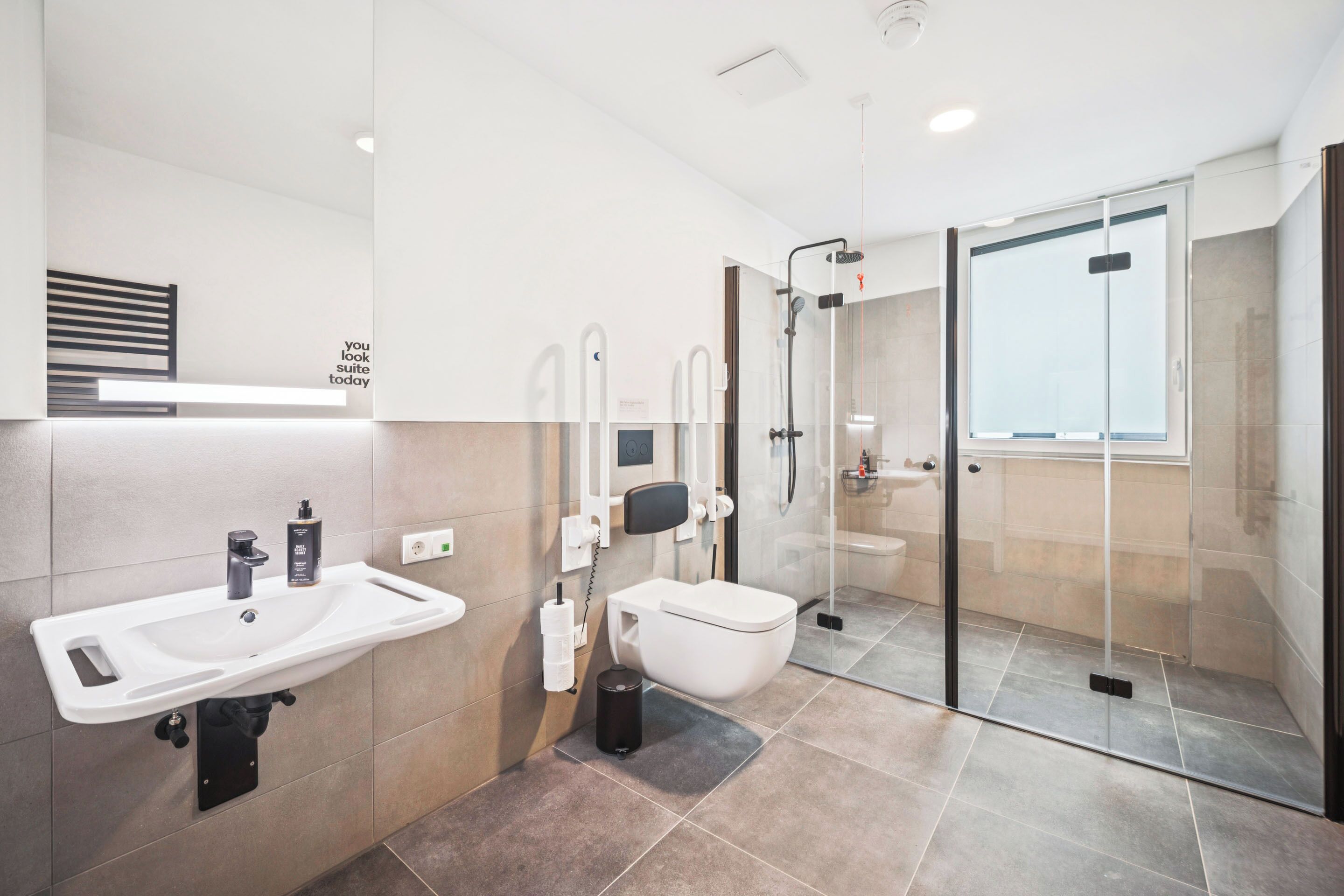A modern bathroom with a white sink, toilet, and glass-enclosed shower.