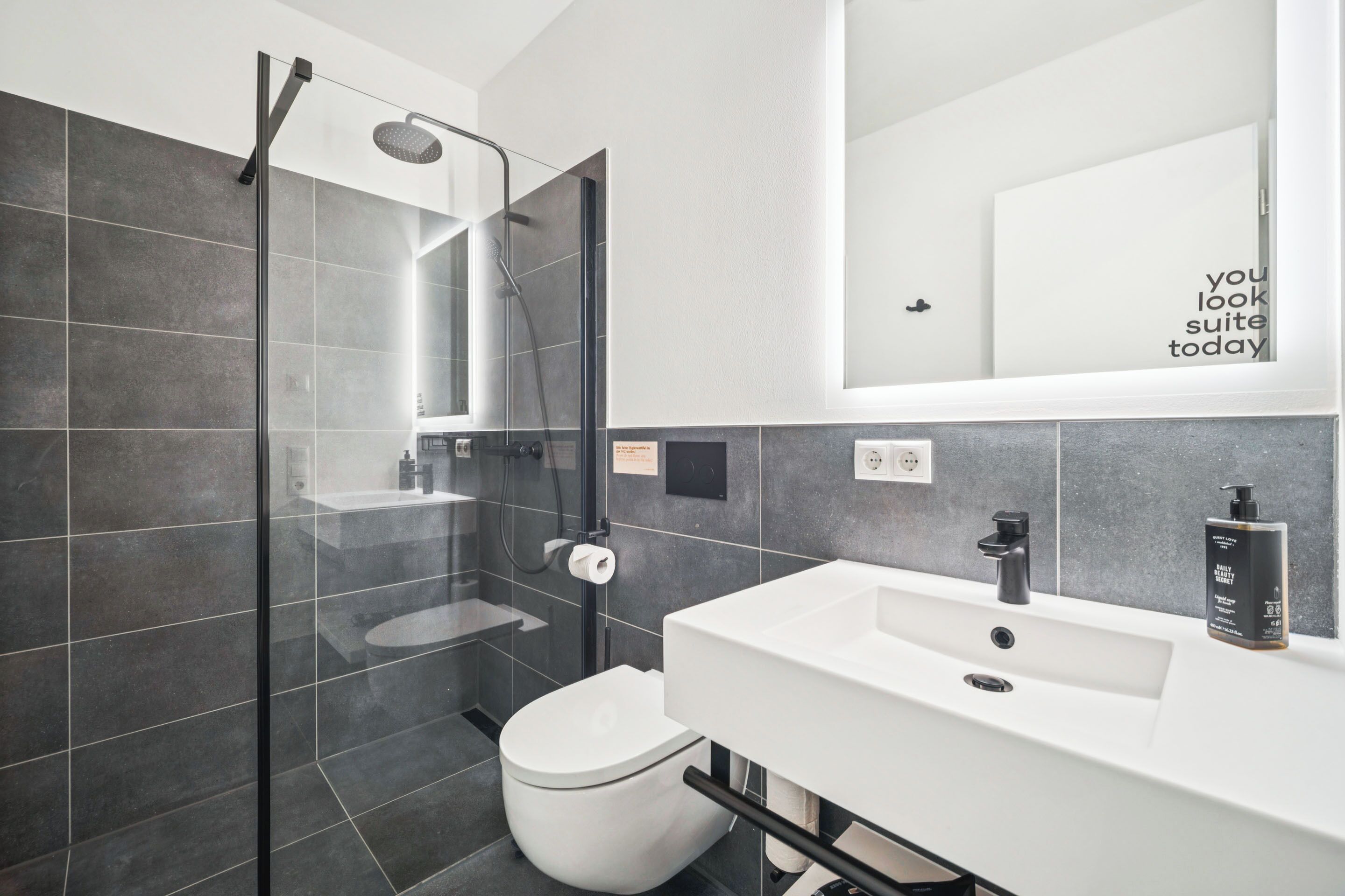 A modern bathroom with a glass-enclosed shower, a white sink, and a toilet.