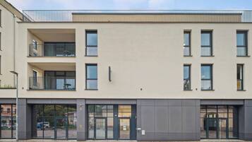 A modern building with a flat facade, large windows, and a gated entrance.