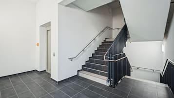 Eine moderne Treppe mit schwarzen Geländern und Handlauf, die zu einer Empfangsebene mit weißer Wand und einer Tür führt.