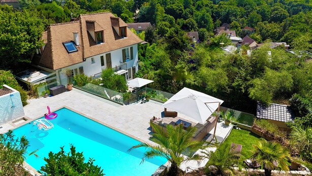 Une propriété résidentielle dotée d’une piscine, d’un patio couvert et d’un jardin luxuriant.