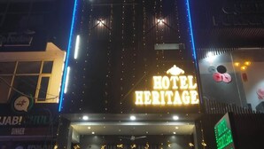 Un hotel llamado 'Hotel Heritage' con un letrero destacado y luces de neón azules.