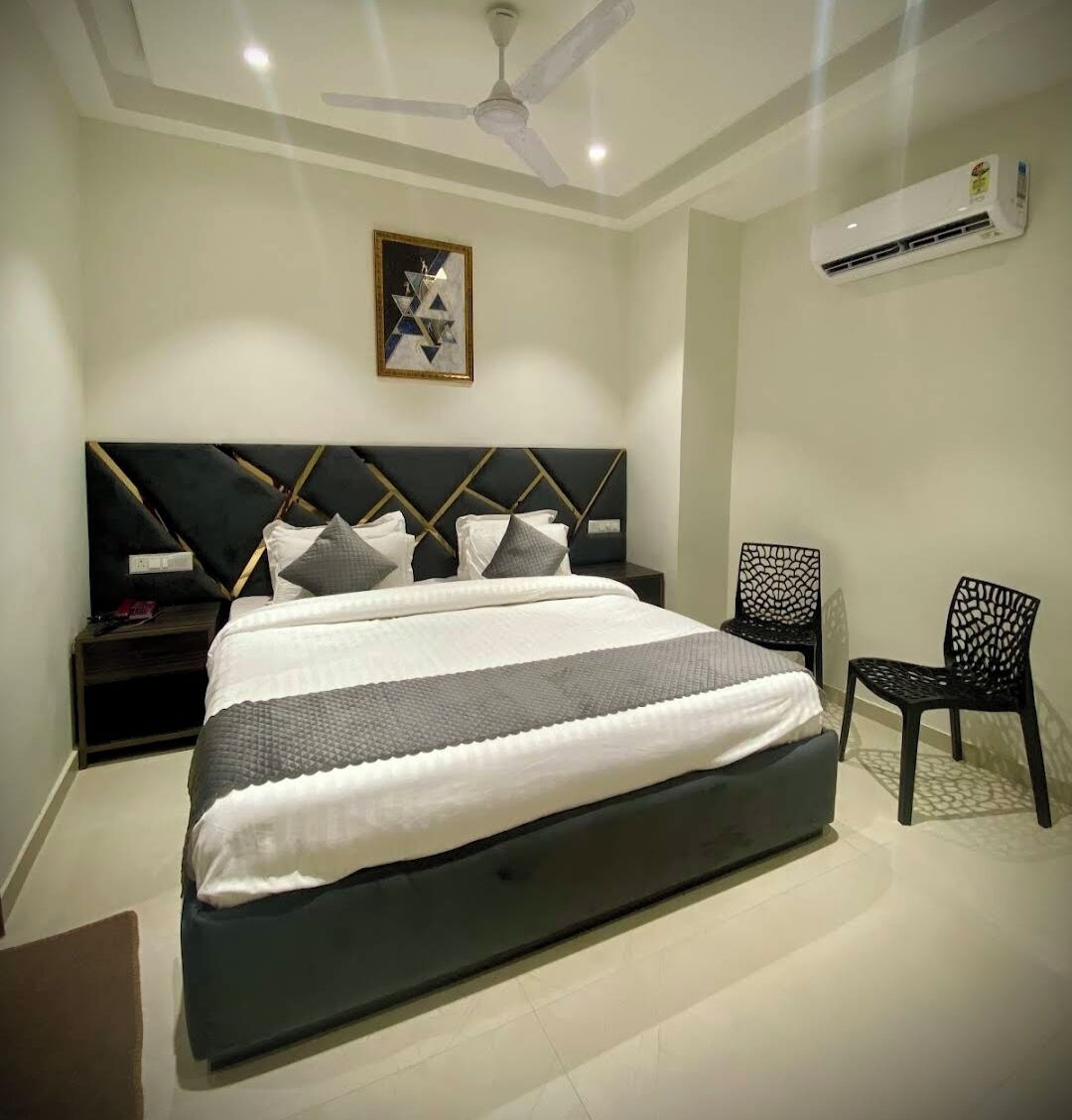 A modern bedroom with a large bed, a ceiling fan, an air conditioner, and a framed artwork on the wall.