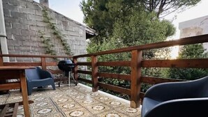 Un'area esterna riparata con pavimento a motivi, ringhiera in legno e posti a sedere.