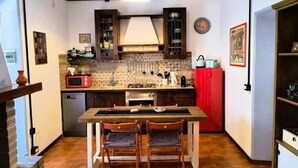 Una cucina compatta con un'isola centrale, un forno a microonde, un fornello e un frigorifero rosso.