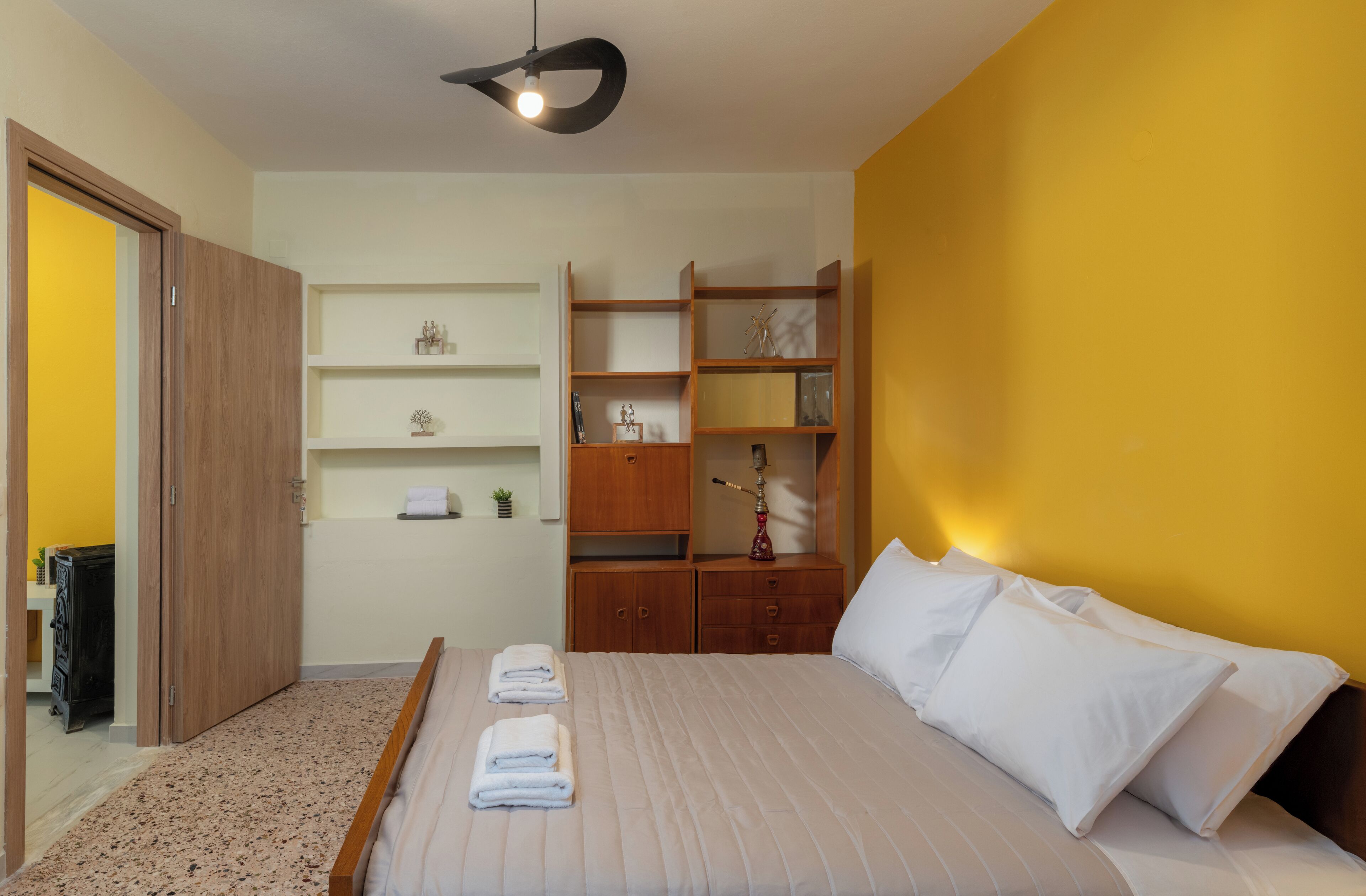 Ein Hotelzimmer mit Bett, Kleiderschrank, Regale und einer Lampe.