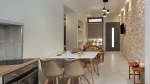 Una cucina moderna con forno integrato, un'area pranzo con tavolo e sedie, e una parete con texture in pietra.
