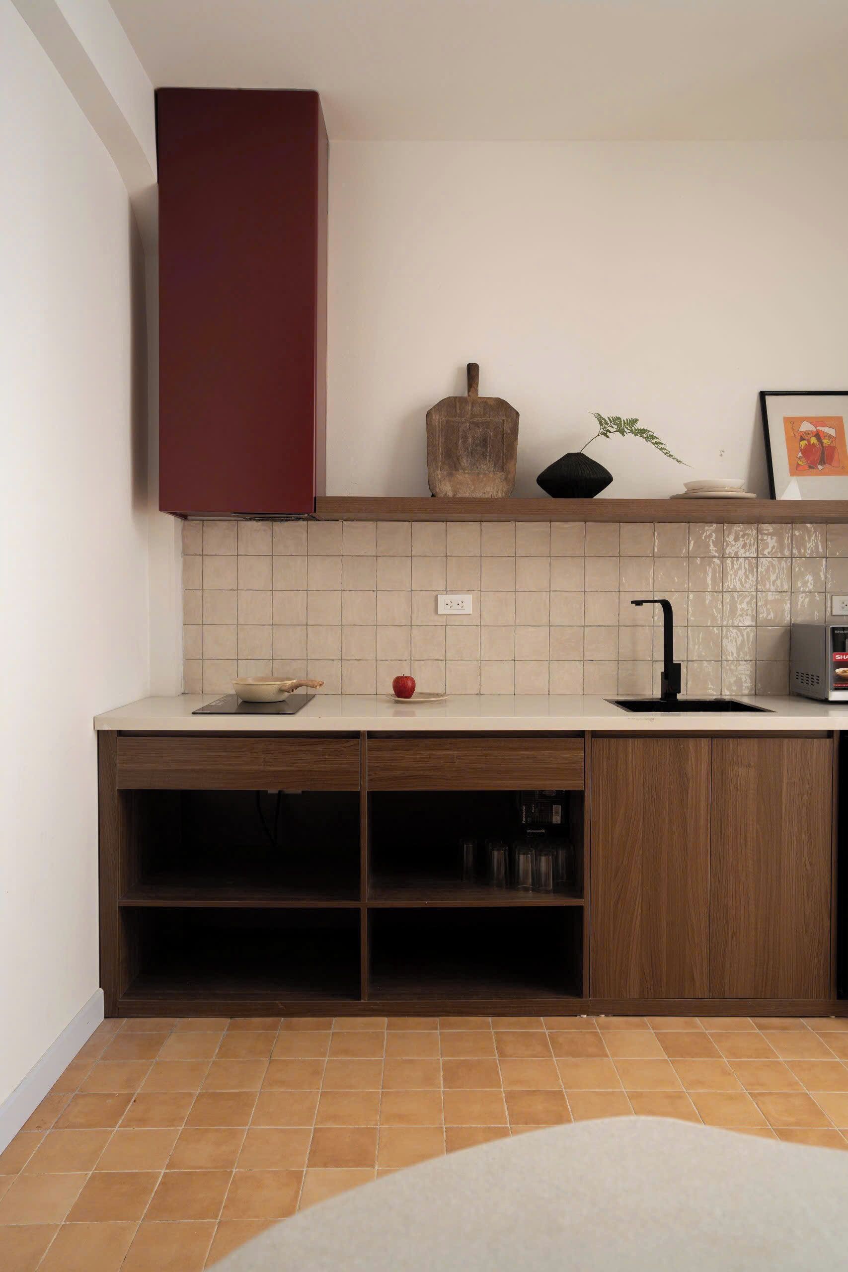 A modern kitchen with a wooden countertop, a red cabinet, a black sink, and a tiled backsplash.