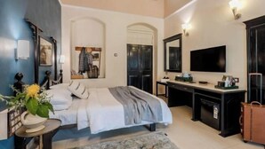 Un dormitorio con cama, escritorio, televisión y maleta.
