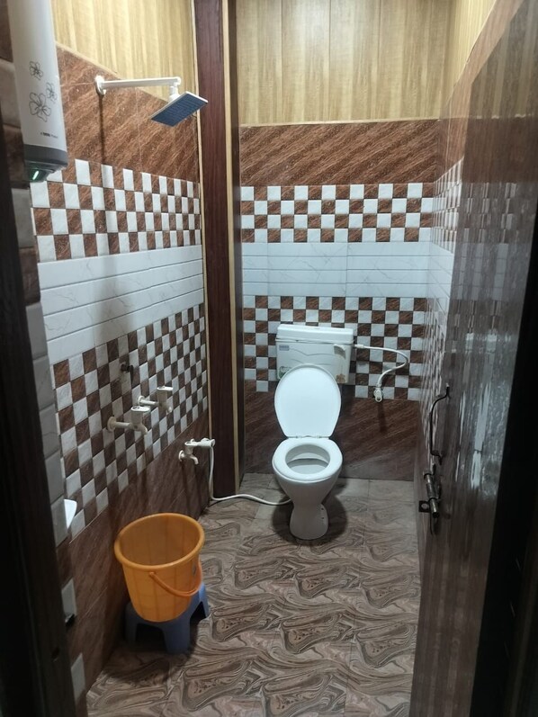 A small bathroom with a toilet, a shower, and a bucket.