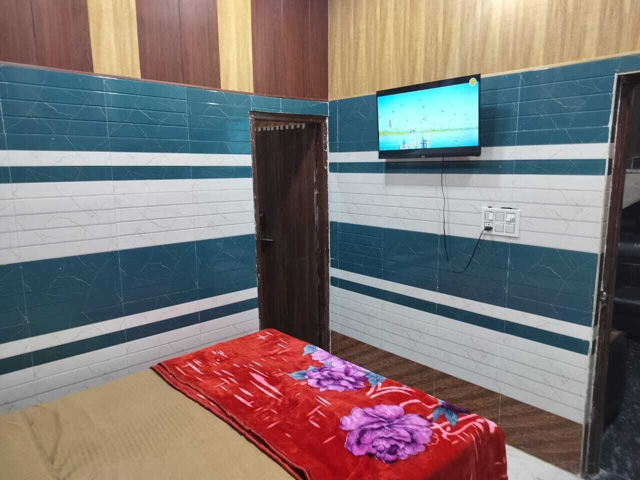 A small room with a bed, a television mounted on the wall, and a door.