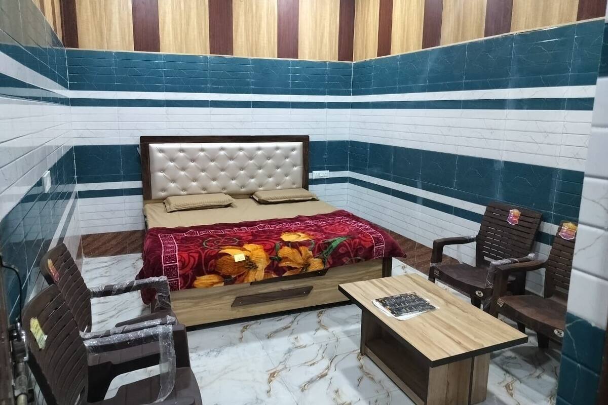 A room with a bed, a wooden table, and two chairs.
