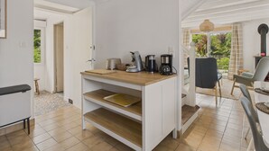 A modern kitchen with white cabinetry, a wooden countertop, and a coffee maker. - Large garden and terrace – 4 adults and 1 child (Fouesnant)