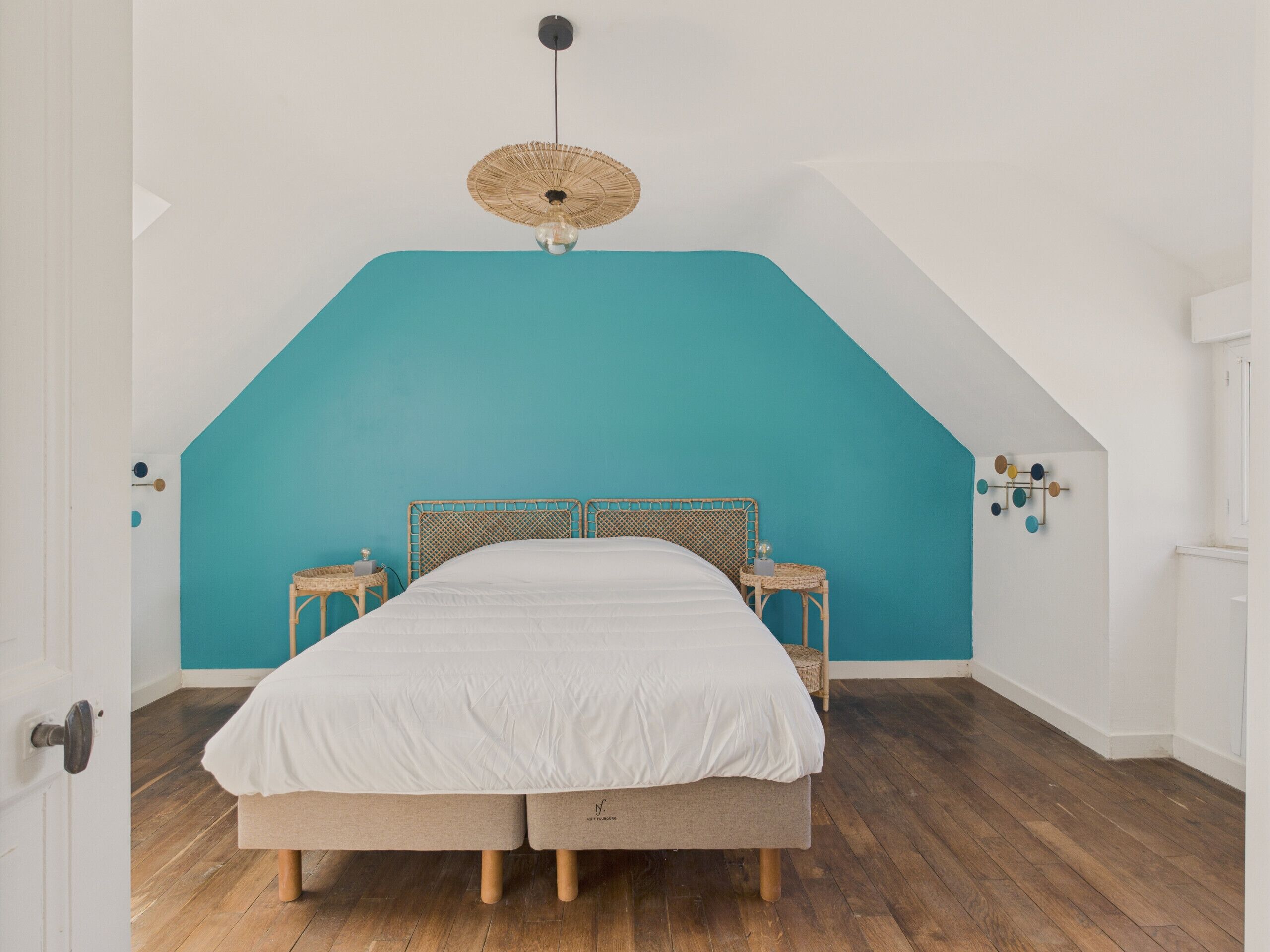 Une chambre à coucher avec un lit, un ventilateur de plafond et un luminaire fixé au mur.