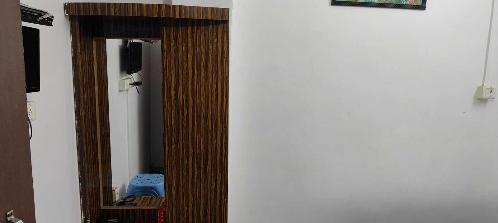 Una puerta con un espejo, un taburete azul y un enchufe en la pared.