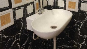 Een badkamer met een witte wastafel, zwart-wit betegelde vloer en een spiegel boven de wastafel.