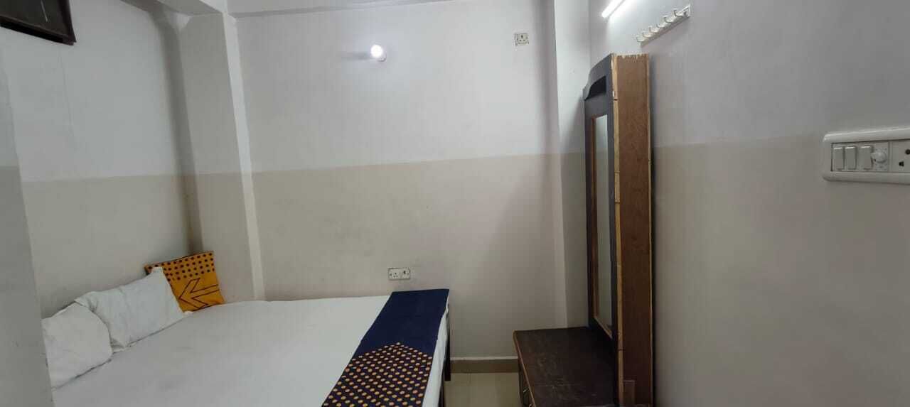 A bedroom with a bed, a bedside table, a mirror, and a wall socket.