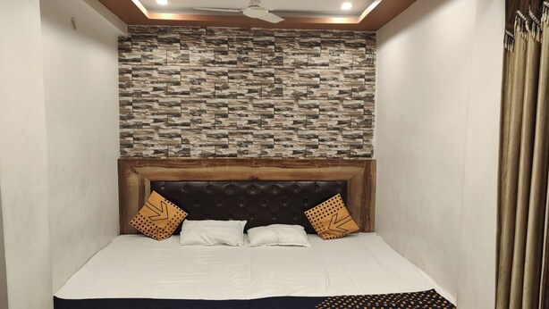 Een slaapkamer met een bed, twee kussens, een houten hoofdbord en een gestructureerde wand boven het bed.