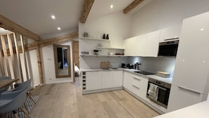 A modern kitchen with white cabinets, a built-in oven, and a microwave.