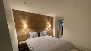 A bedroom with a wooden headboard, two bedside lamps, a large bed, and a patterned rug.