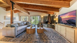 Una sala acogedora con chimenea, televisor grande y una pared de detalles de piedra.