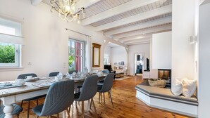 Een ruime eethoek met een houten tafel, stoelen en een kroonluchter.