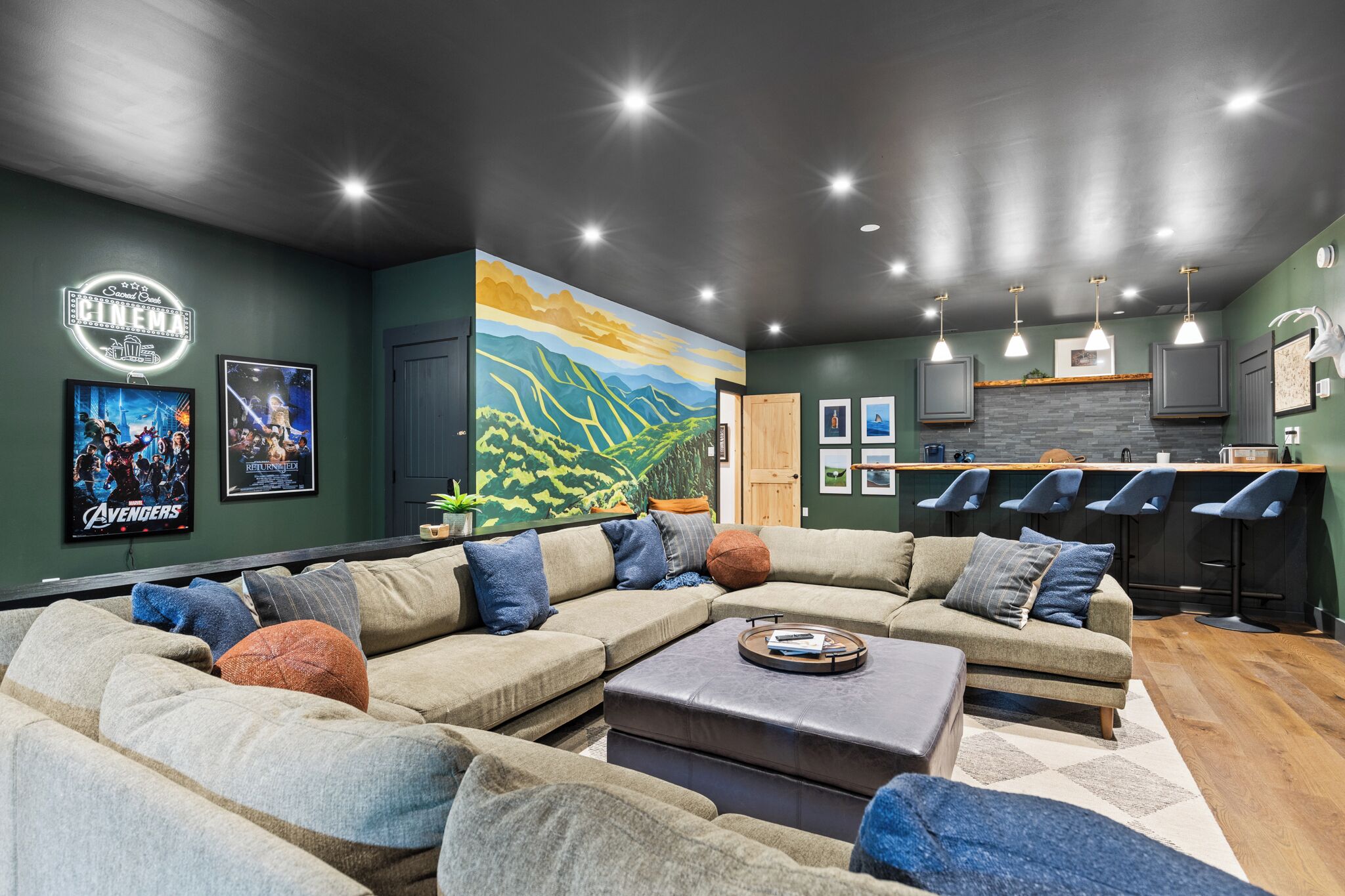 A modern living room with a sectional sofa, a coffee table, and a mural on the wall.