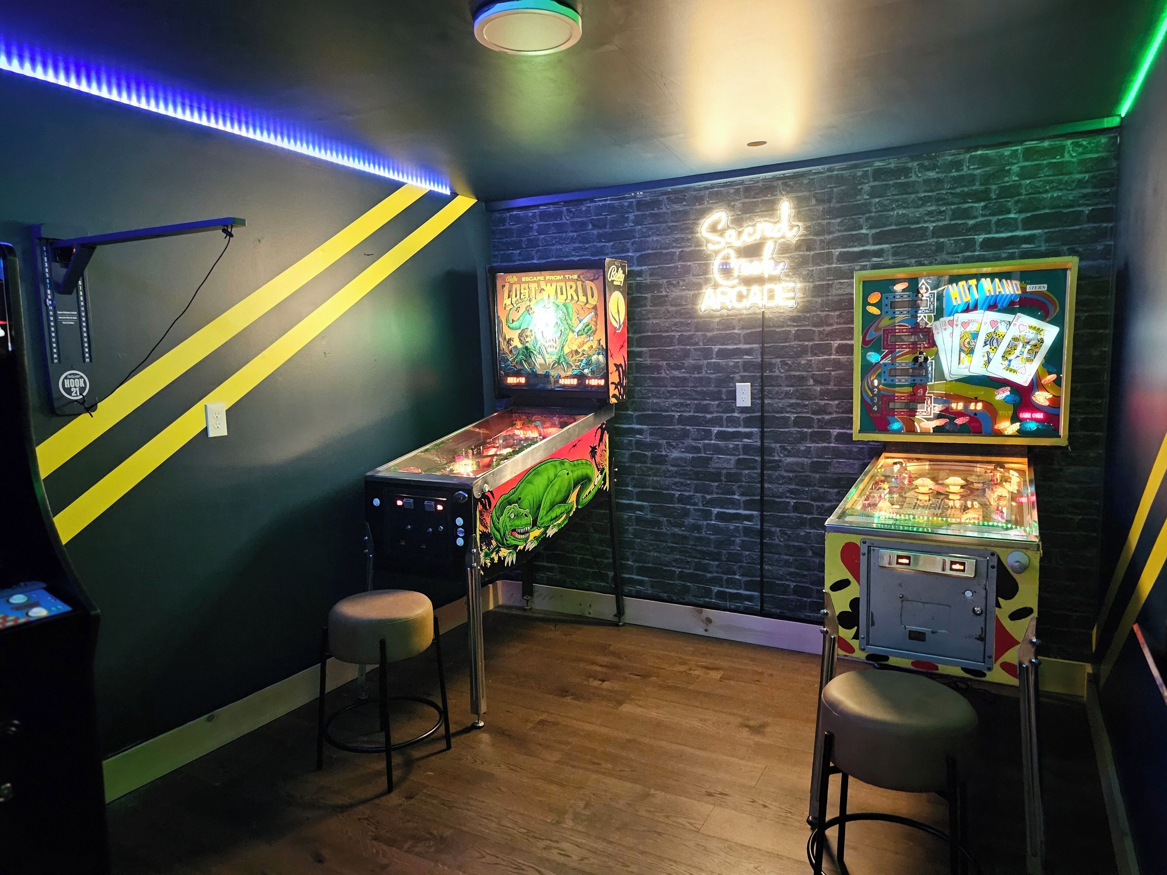 A room with arcade games, a neon sign, and a brick wall.