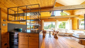 A spacious living area with a wooden floor, a central island with a sink, and a kitchen area with a black countertop and wooden cabinets. - "Whisper of Alpacas" chalet (Oederan)