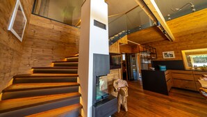 A modern interior with a wooden staircase, a kitchen area, and a glass railing. - "Whisper of Alpacas" chalet (Oederan)