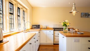 A kitchen with a wooden countertop, white cabinets, a built-in oven, and a window with a view. - Hopscotch House - Stanton near Broadway (Near Broadway)