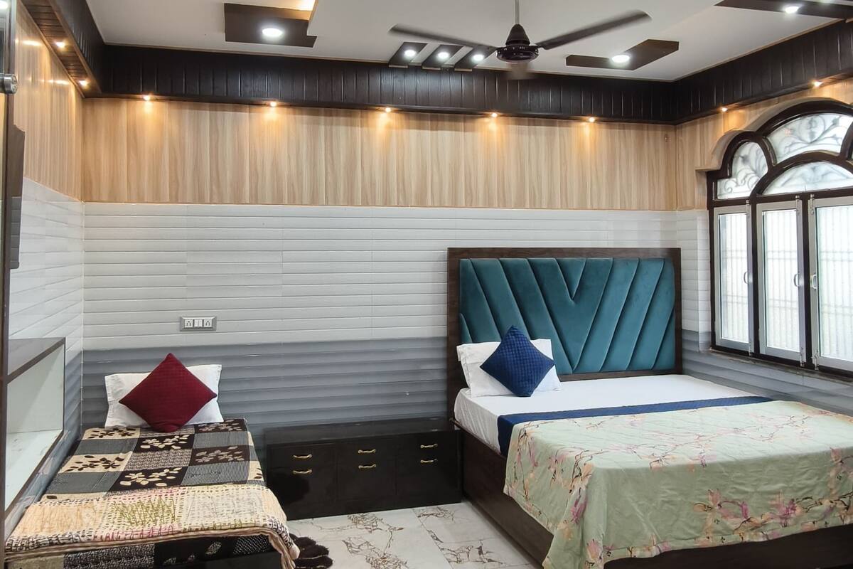 A modern bedroom with two beds, a desk, and a ceiling fan.