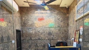A reception area with a neon sign for 'Hotel Samtsha Inn', a ceiling fan, and a reception desk. - Hotel Samiksha Inn (Ayodhya)