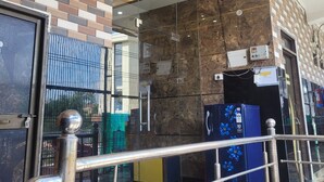 A hotel entrance with a tiled wall, a glass door, and a metal railing. - Hotel Samiksha Inn (Ayodhya)