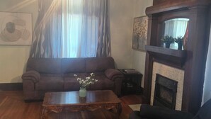 A living room with a wooden floor, a sofa, a coffee table with a vase, a fireplace, and a chandelier. - Spacious 5-bedroom house in brilliant Cincinnati with WiFi, AC (Cincinnati)
