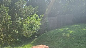 A backyard with a brick wall, a black trash can, and a wooden fence. - Spacious 5-bedroom house in brilliant Cincinnati with WiFi, AC (Cincinnati)