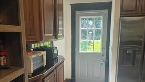 A kitchen with wooden cabinets, a microwave, a refrigerator, and a door with a window. - Spacious 5-bedroom house in brilliant Cincinnati with WiFi, AC (Cincinnati)