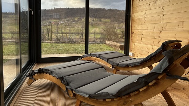 Una habitación con dos sillones de madera orientados hacia un ventanal con vistas a un paisaje rural.