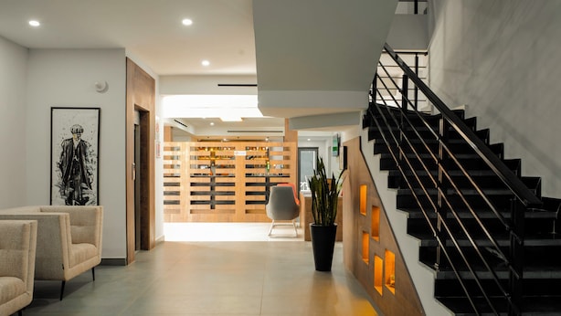Un intérieur moderne avec un escalier, un coin salon et une cloison en bois dotée d’étagères.