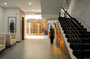 Un intérieur moderne avec un escalier, un coin salon et une cloison en bois dotée d’étagères.