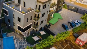 Un immeuble à plusieurs étages doté d’une terrasse sur le toit, d’une piscine et d’un espace de stationnement.