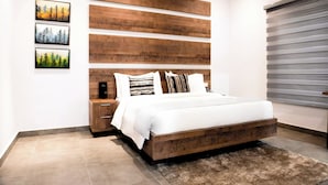 Une chambre à coucher moderne avec une tête de lit en bois, un grand lit, une table de chevet et une étagère fixée au mur.