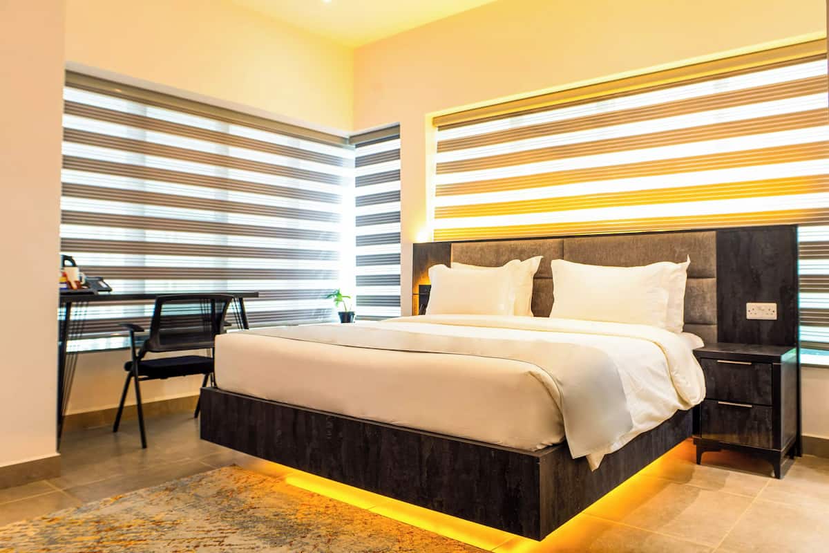 A modern bedroom with a large bed, bedside tables, a desk, and a chair.