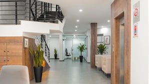 Un hall d’hôtel moderne avec un escalier, un espace salon et des plantes en pot.