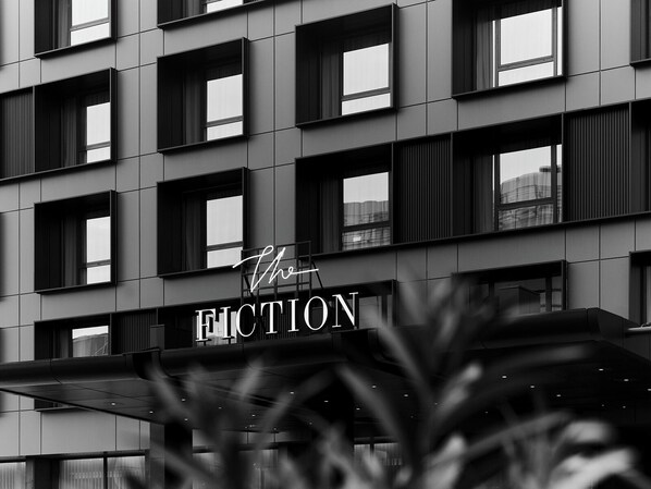 Une façade moderne avec une enseigne indiquant « The Fiction » et de nombreuses fenêtres.