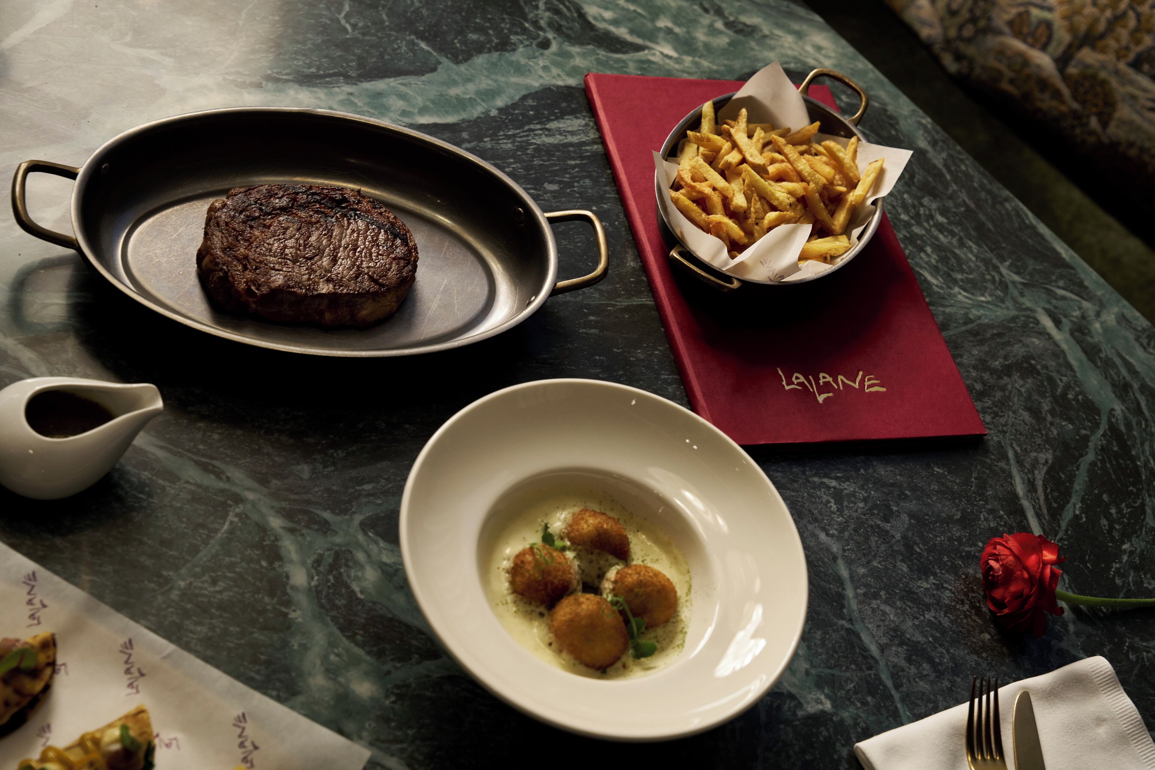Ein Steak, Pommes und eine Schüssel Knödel auf einem Tisch.