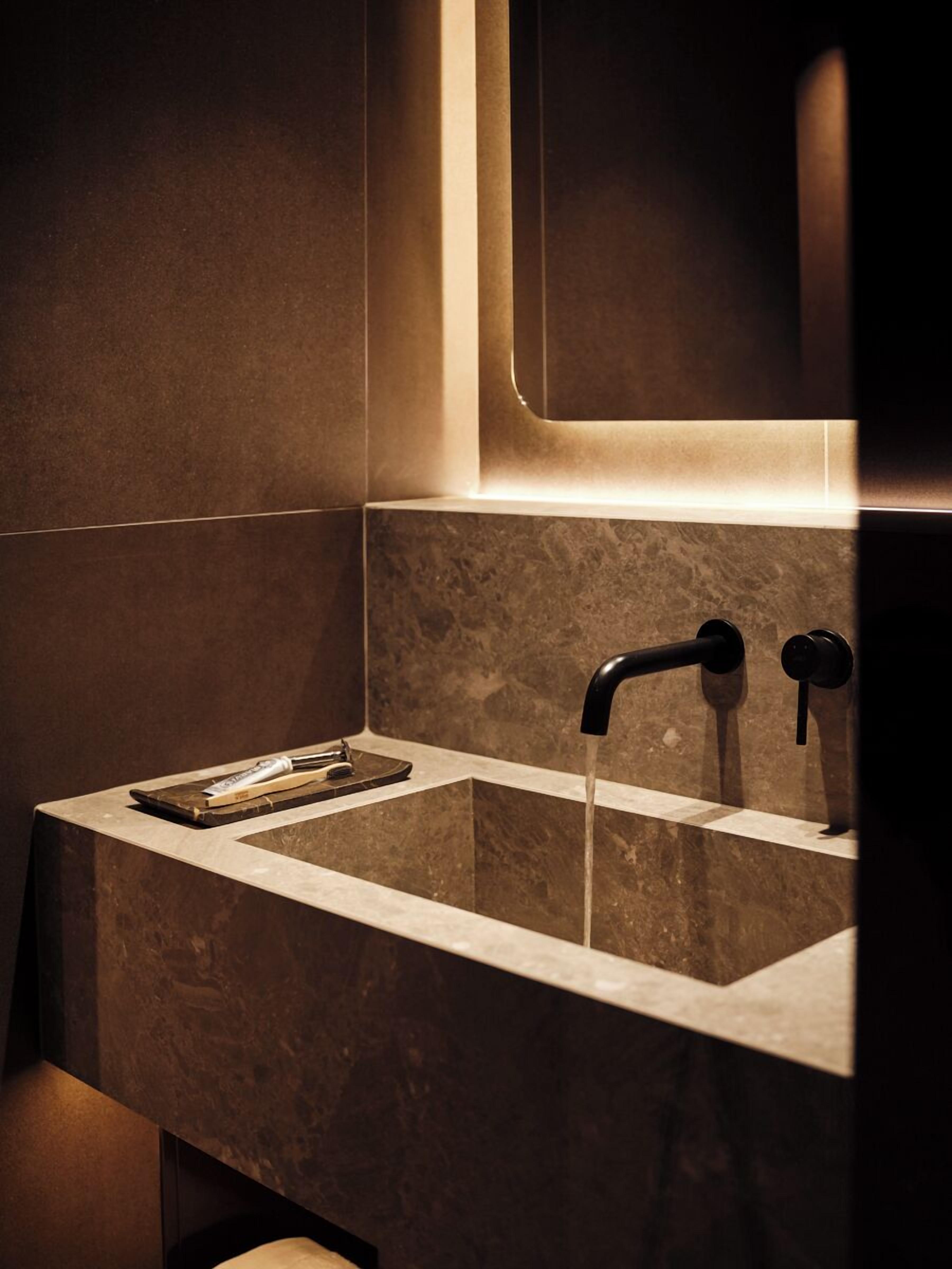 Une salle de bain moderne avec un lavabo rectangulaire, deux robinets et un miroir au-dessus.