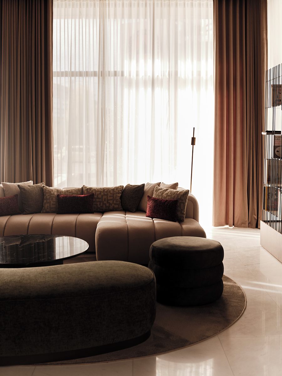 Ein modernes Wohnzimmer mit einer Couch, einem Hocker und einer Stehlampe.