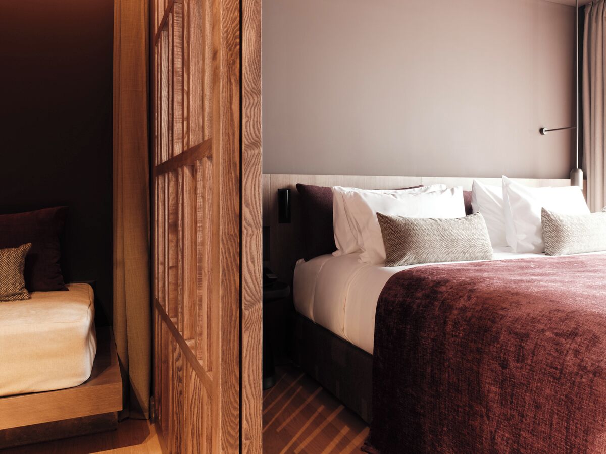 A hotel room with a bed, a nightstand, and a wooden panel wall.
