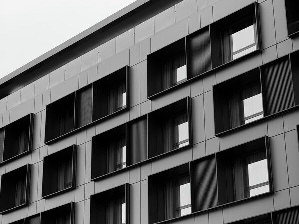 Un bâtiment moderne doté d’une grille de fenêtres rectangulaires et d’une façade plane.
